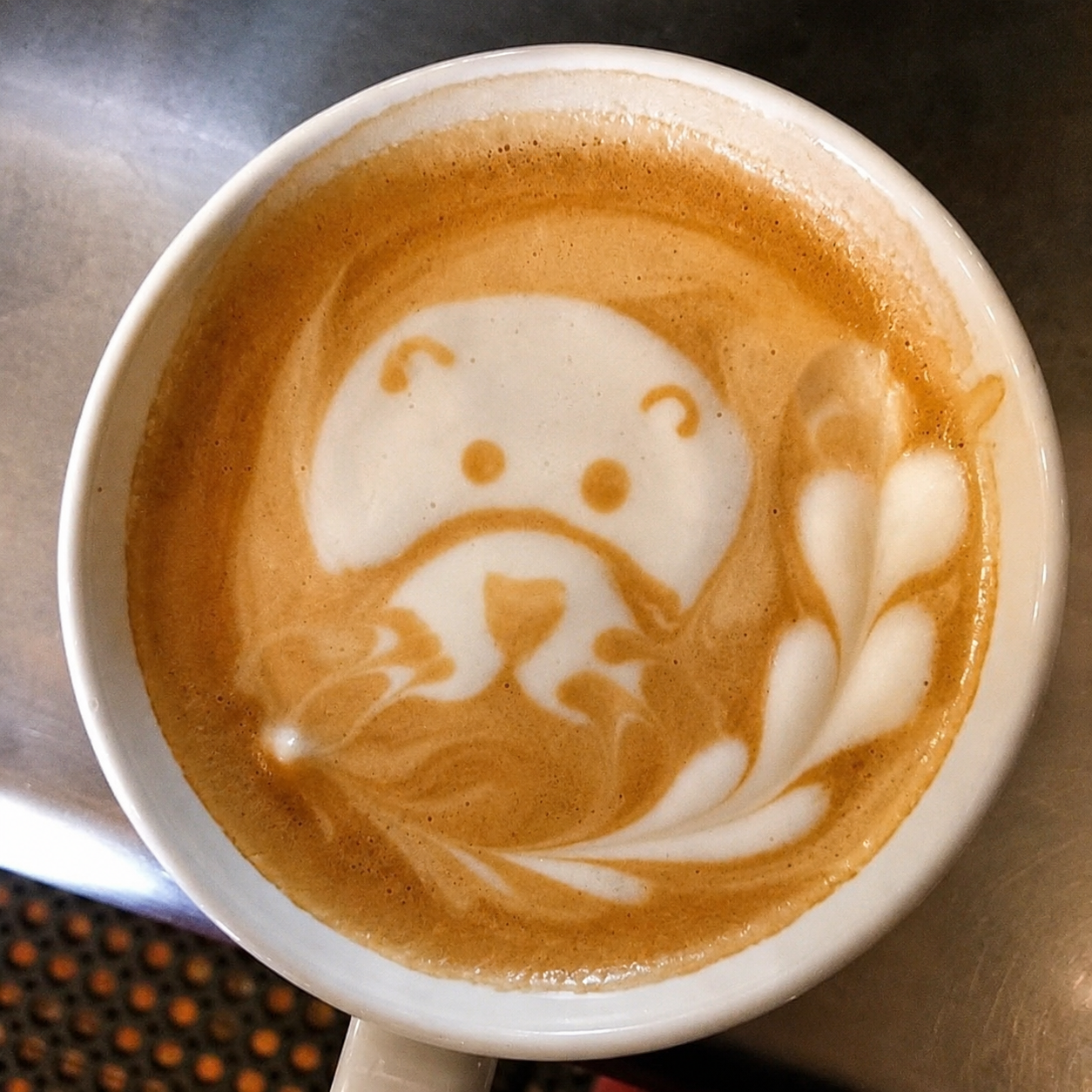 Coffee with character-shaped latte art in a white cup
